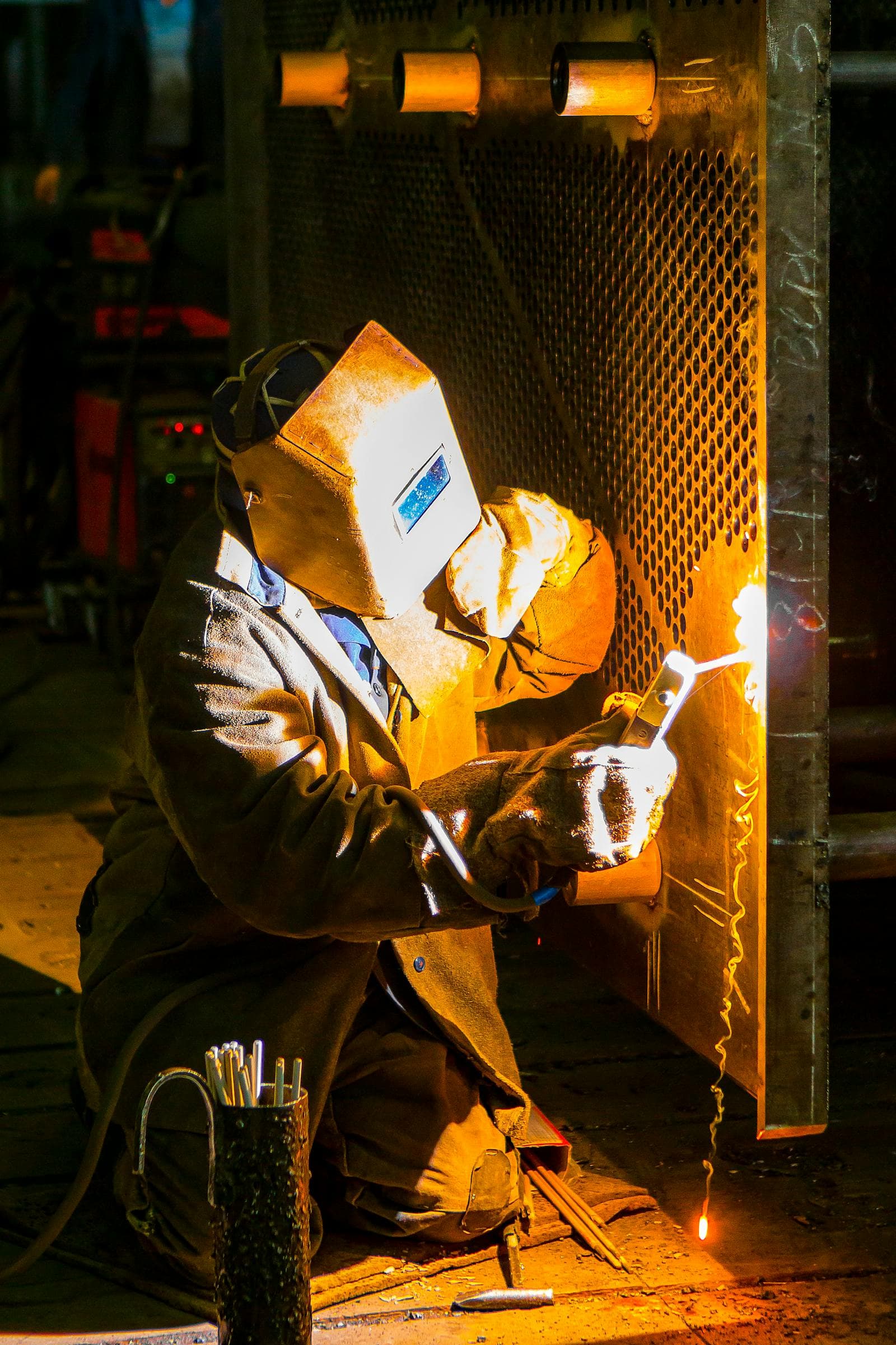 Shop welder mid-cut with sparks flying